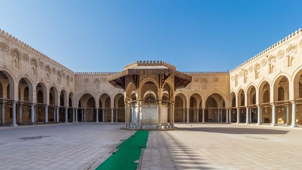 Ablution fountain mediating the courtyard of public historic mosque of Sultan al Muayyad, with background of arched corridors surrounding the courtyard, Cairo, Egypt