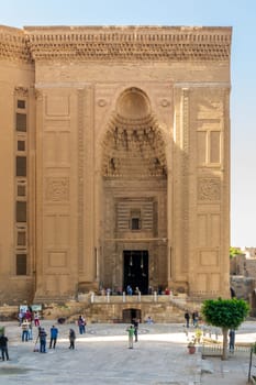 Cairo, Egypt - November 27 2021: Facade of Islamic Mamluk era Mosque and Madrassa of Sultan Hassan, with few visitors, Old Cairo