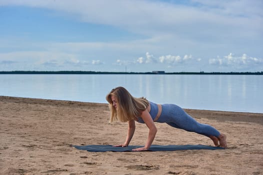Woman doing yoga on the sandy beach. High quality photo