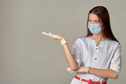 A female doctor in a medical mask points to an empty place, copy space. High quality photo