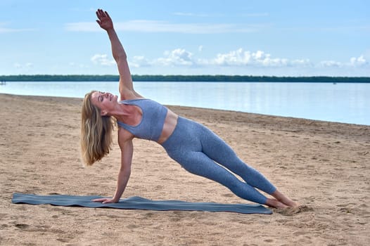 Woman doing yoga on the sandy beach. High quality photo