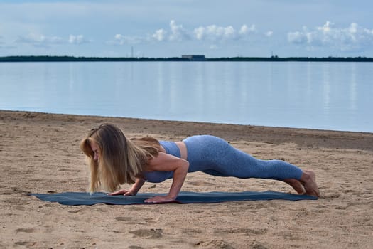 Woman doing yoga on the sandy beach. High quality photo