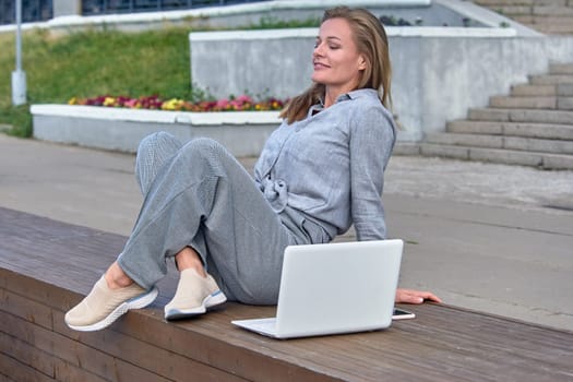 Woman with laptop sitting on a bench and resting. High quality photo