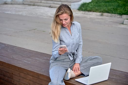A woman with a laptop sits on a wooden platform, works online. High quality photo