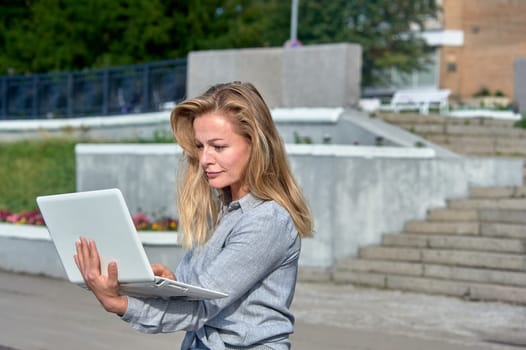 A woman with a laptop sits on a wooden platform, works online. High quality photo