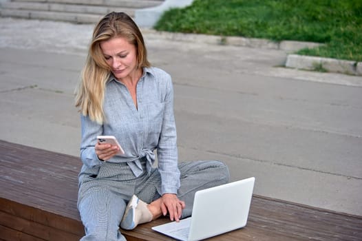 A woman with a laptop sits on a wooden platform, works online. High quality photo