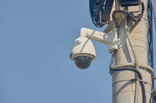 A surveillance surveillance camera is hanging on a pole. High quality photo