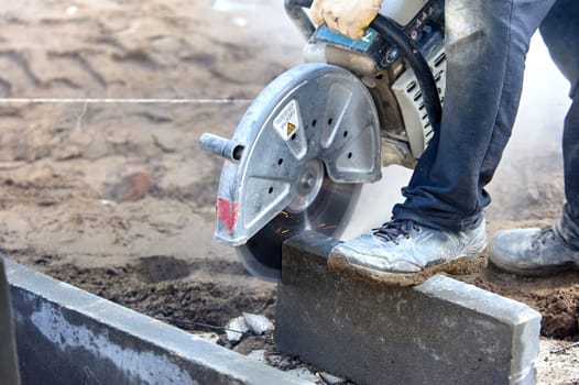 A worker with a circular saw cuts a curb stone close-up. High quality photo