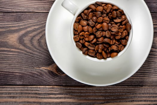A white coffee mug filled with fragrant coffee beans stands on an old tree. High quality photo