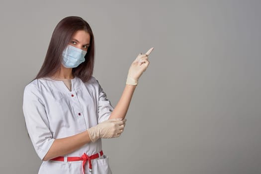 A female doctor in a medical mask points to an empty place, copy space. High quality photo