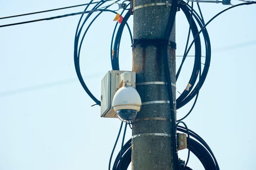 A surveillance surveillance camera is hanging on a pole. High quality photo
