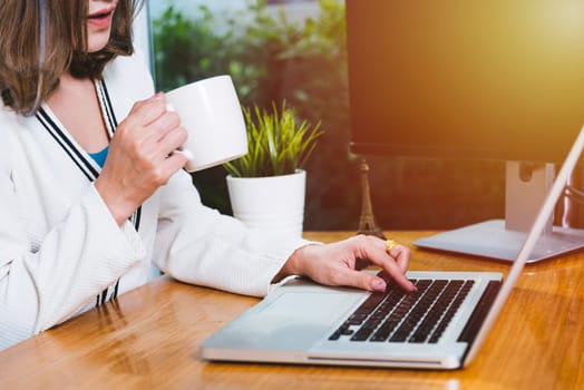 Beautiful business woman lifestyle working using laptop computer and hold coffee cup on hand