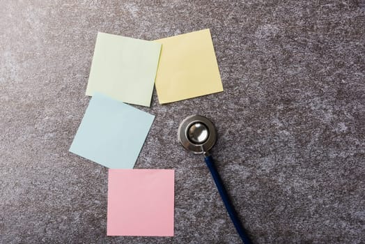 Above blank paper stick note list yellow, green, pink and blue with doctor stethoscope on concrete background, Health reminder concept