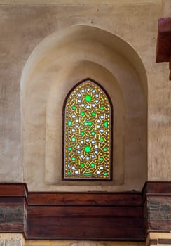 Perforated stucco window decorated with colorful stain glass with geometrical circular patterns and floral patterns, located at Mamluk era public historical Qalawun complex, Moez Street, Cairo, Egypt