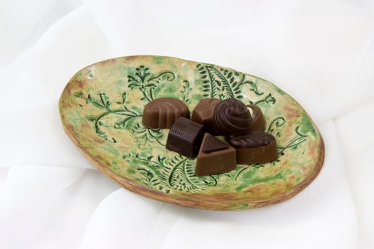 a lot of variety chocolate pralines on a clay plate - white backgrund