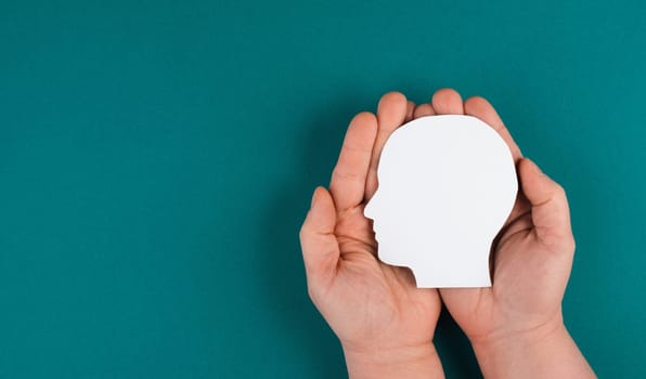 Holding a paper cut out head in the palms, symbolic for brainstorming, having an idea, new concepts, copy space for text