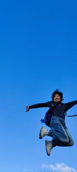 The girl in a jump. Young beautiful woman posing against blue sky bright sunny weather