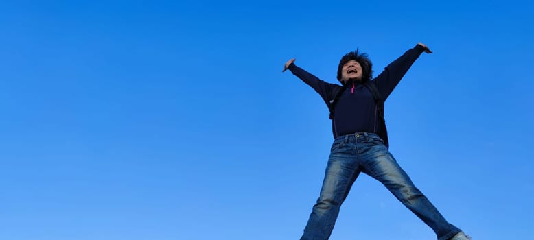 The girl in a jump. Young beautiful woman posing against blue sky bright sunny weather