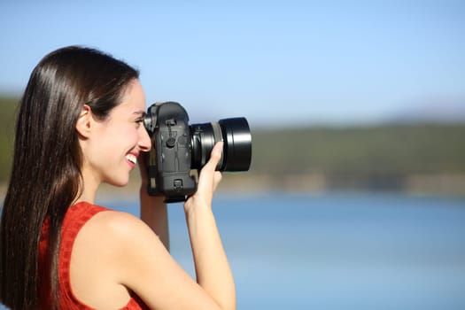Side view portrait of a happy photographer taking photos in a lake