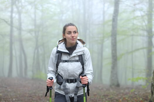 Front view portrait of a happy trekker woman walking in a forest in winter
