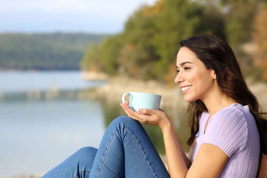 Side view portrait of a happy woman drinking coffee contemplating in nature