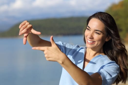 Happy woman framing with hands standing outdoors in nature