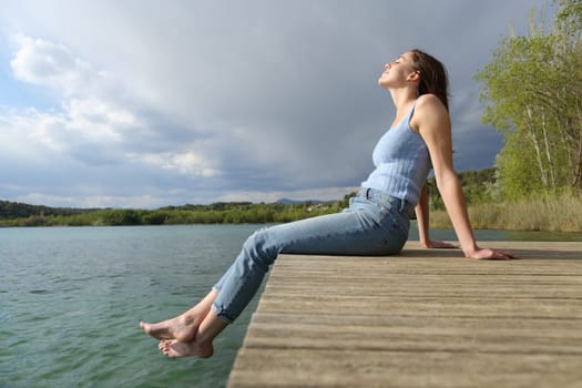 Side view portrait of a beautiful woman relaxing sitting in a pier