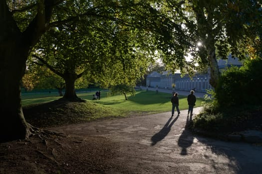 Sheffield, United Kingdom, 21st October, 2021: A silhouetted couple walk towards iconic greenhouses near main entrance of sheffield botanical gardens