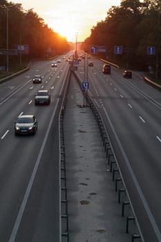 Moving cars on the motorway at sunset time. Highway traffic at sunset with cars. Busy traffic on the freeway, road top view