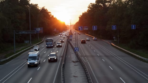 Moving cars on the motorway at sunset time. Highway traffic at sunset with cars. Busy traffic on the freeway, road top view
