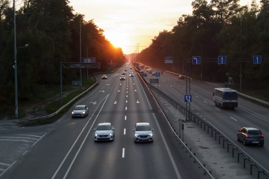 Moving cars on the motorway at sunset time. Highway traffic at sunset with cars. Busy traffic on the freeway, road top view