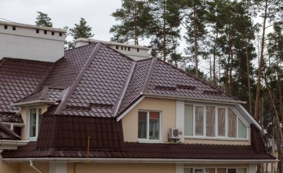 Roof on residential property with new brown corrugated metal roof tiles. Modern metal roof. Metal roofing