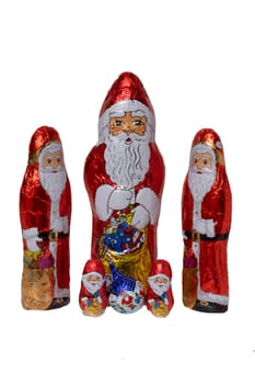 Chocolate Santa isolated. Close-up of five cheerful wrapped chocolate Santa Claus or the good Saint Nicolas figurine isolated on a white background. Macro photograph.