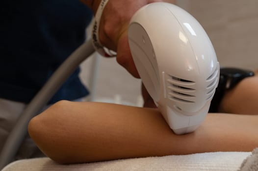 The doctor does the Rf lifting procedure on the inner side of the forearm of a woman in a beauty clinic.
