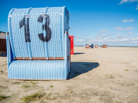 Rear view of a light blue beach chair on the German North Sea coast in summer against a blue sky.
