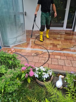 Man cleaning conservatory with a pressure washer - high pressure washer on patio glass surface