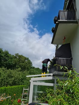 Man cleaning conservatory with a pressure washer - high pressure washer on patio glass surface