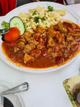 Tasty stuffed beef chunks or beef stroganoff with pasta fussili served on plate. View from above.