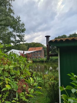Red bricks house in countryside near the lake with mirror reflection in water