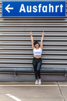 Young woman stretching out arms showing blue exit sign