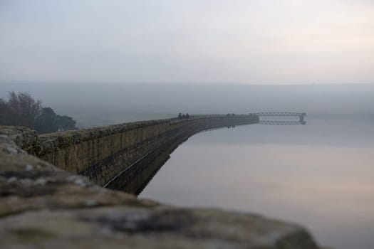 Sheffield, United Kingdom, 7th November, 2020: People enjoy a winters walk along redmires dam wall. Misty and foggy conditions surround the jetty