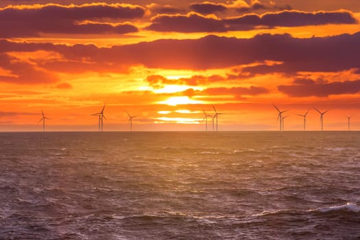 Sunrise at decarbonization industry windmills business for regenerative energies. Clean energy renewables preventing climate change.