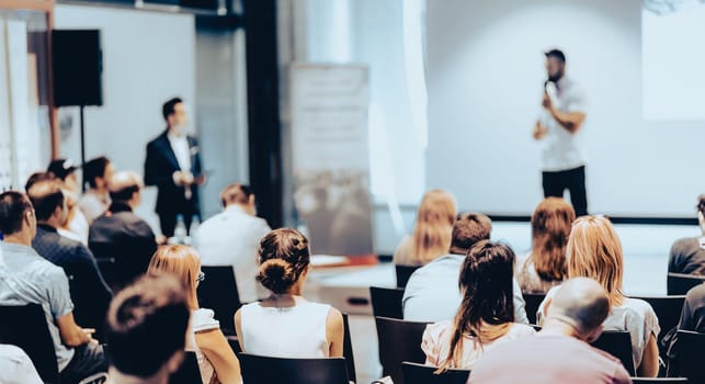 Speaker giving a talk in conference hall at business event. Rear view of unrecognizable people in audience at the conference hall. Business and entrepreneurship concept.