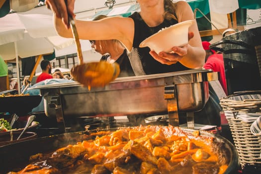 Cheff serving fusion international cusine on street stall on international street food festival of Odprta kuhna, Open kitchen event, in Ljubljana, Slovenia.