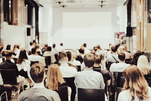 Speaker giving a talk in conference hall at business event. Rear view of unrecognizable people in audience at the conference hall. Business and entrepreneurship concept.
