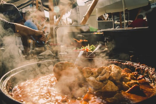 Cheff serving fusion international cusine on street stall on international street food festival of Odprta kuhna, Open kitchen event, in Ljubljana, Slovenia.
