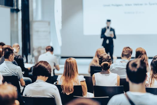 Speaker giving a talk in conference hall at business event. Rear view of unrecognizable people in audience at the conference hall. Business and entrepreneurship concept.