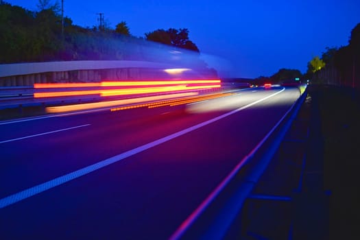 Evening shot of trucks doing transportation and logistics on a highway. Highway traffic - motion blurred truck on a highway-motorway- speedway at dusk.