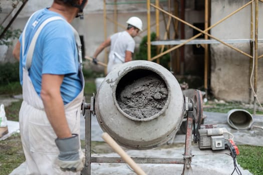 builder laborer man working with front of concrete cement mixer at construction site