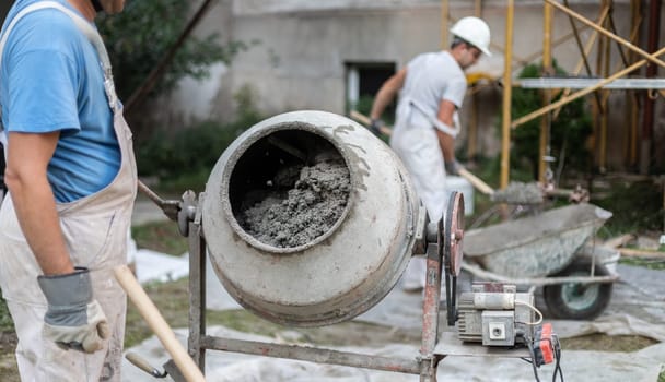 builder laborer man working with front of concrete cement mixer at construction site
